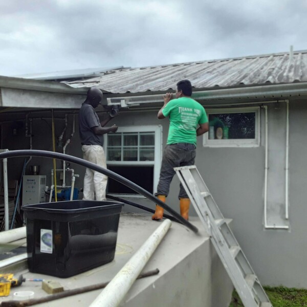 Rosvelt and Joe Saravia connecting the new rain gutters to the water tank